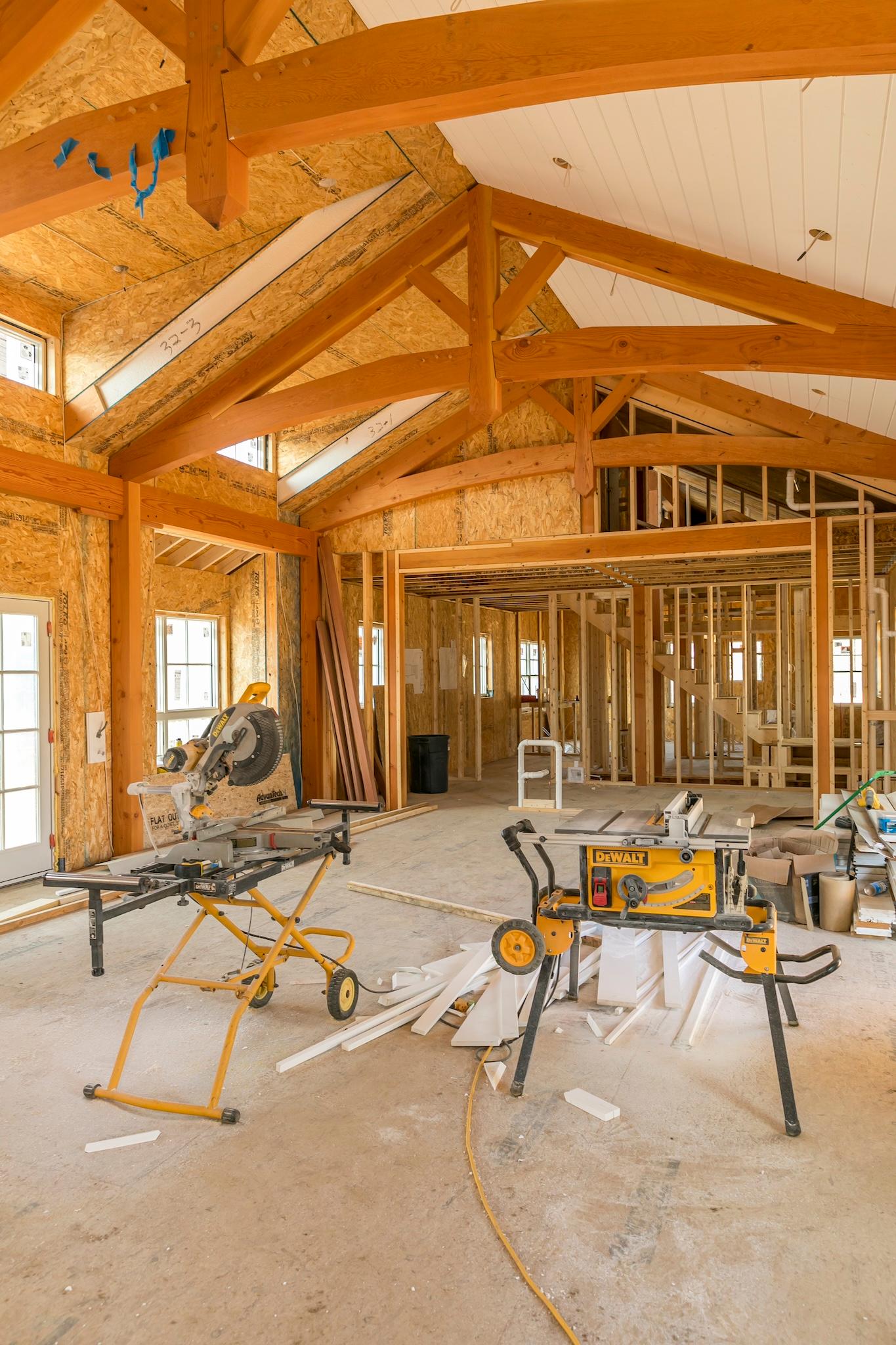 Interior of a Chilmark construction project with post & beam rafters, a chop saw, and a table saw. Framed interior.