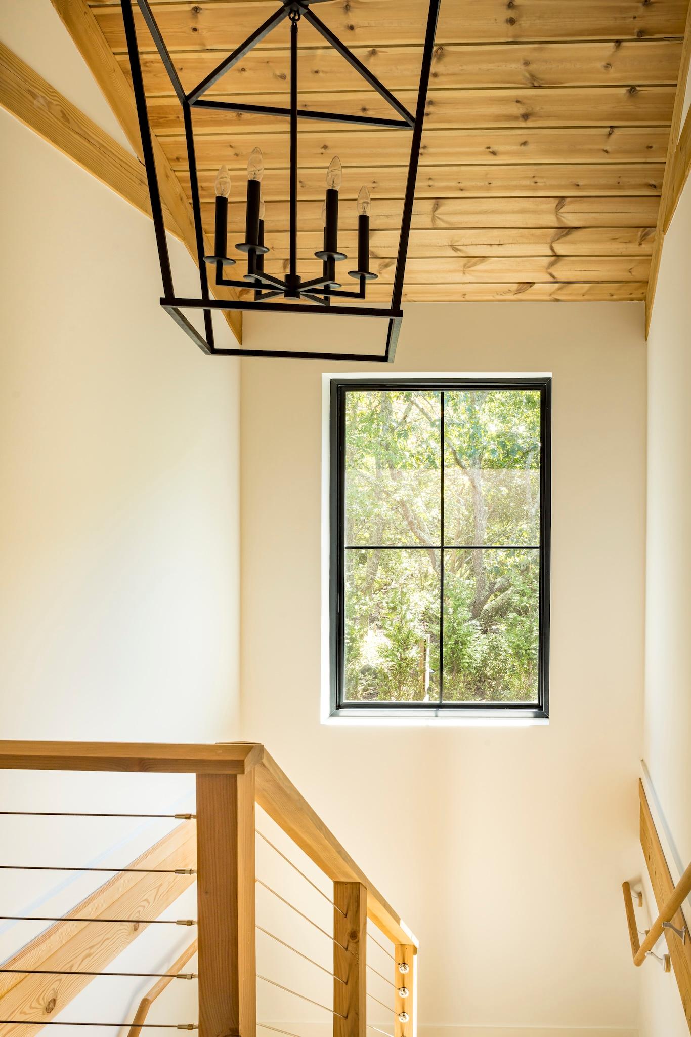 Nature-infused stairwell with a black caged chandeleir