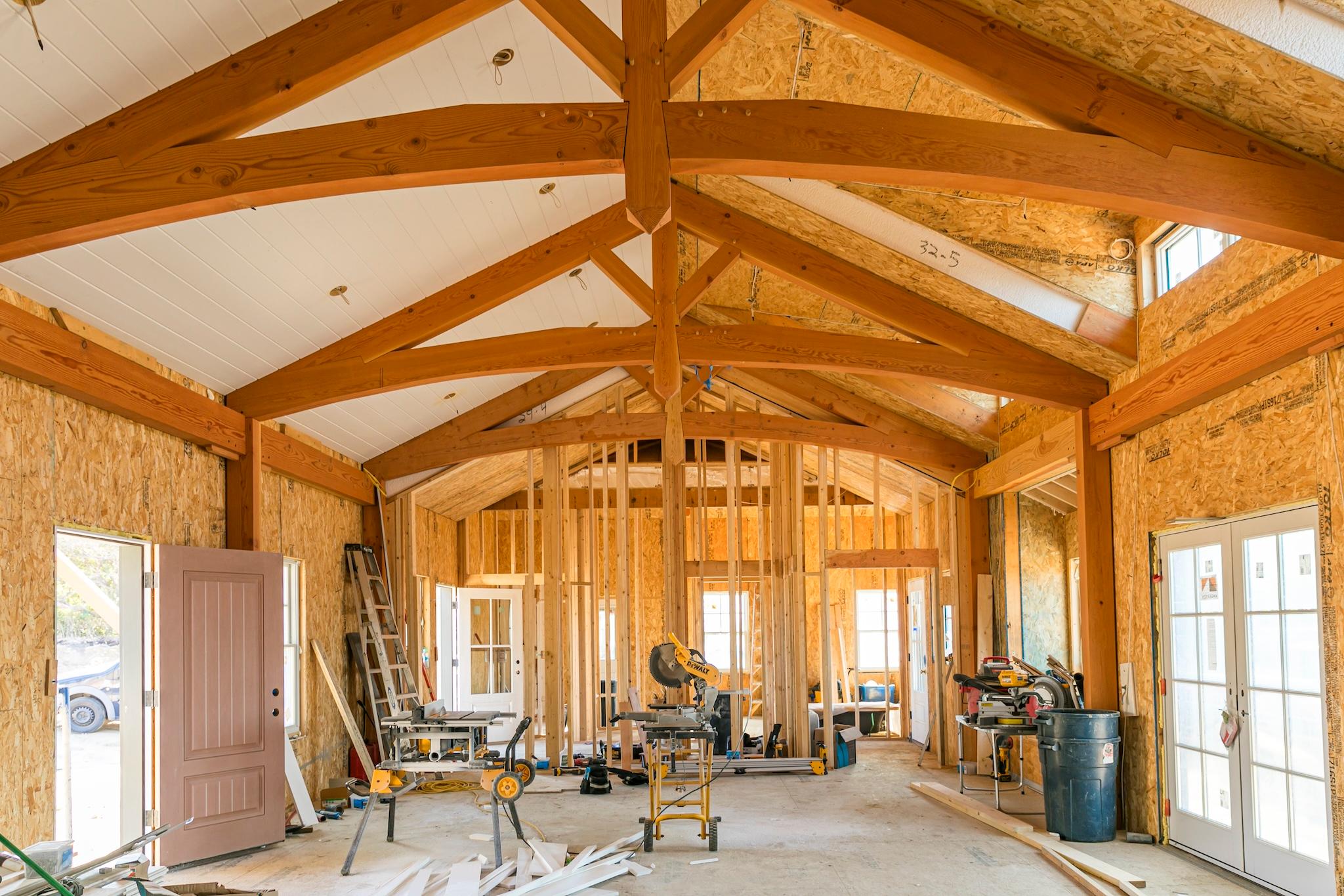 Home construction work in progress with framed interior, post & beam rafters, and equipment