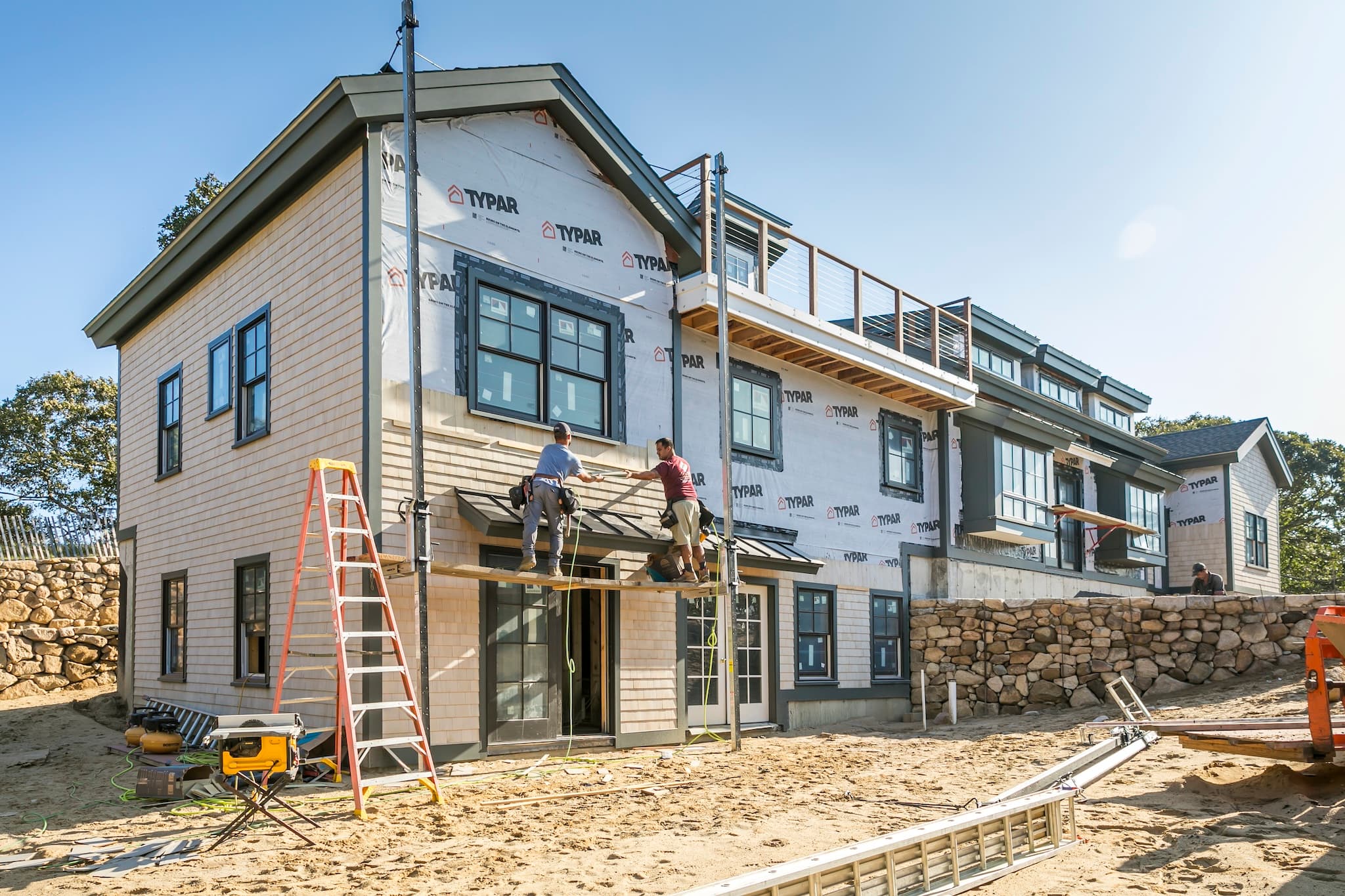 Two Tekton employees collaboratively installing shingles on an up-island home construction project